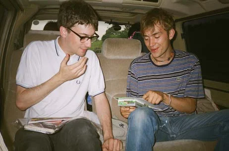 Two young men sitting in the back of a van looking at photographs