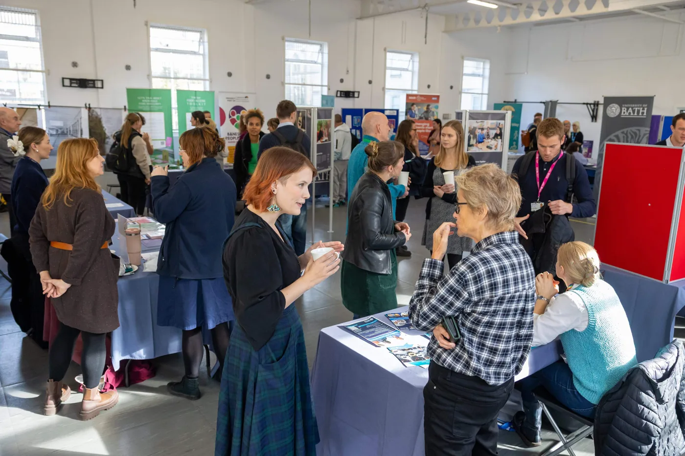Visitors talking at research stalls beside a University of Bath banner