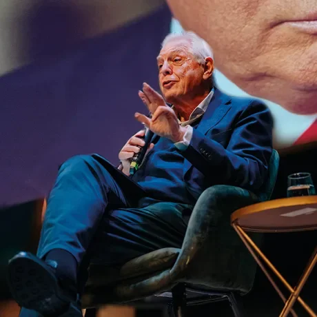John Simpson speaking from an armchair on stage